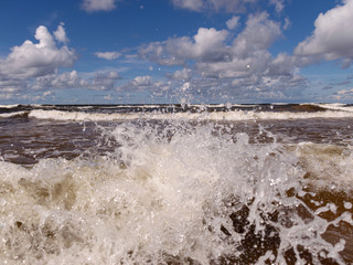blurred foreground with sparkling waves, clouds and sea in the background