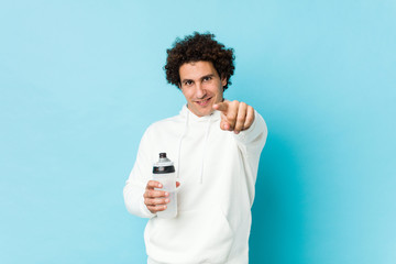 Sport man holding a water bottle cheerful smiles pointing to front.