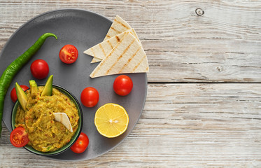 Traditional latin, mexican guacamole sauce in a clay bowl. Ingredients for homemade guacamole: avocado, lemon, salt and pepper and tomatoes and tartilla. top view. Copy space