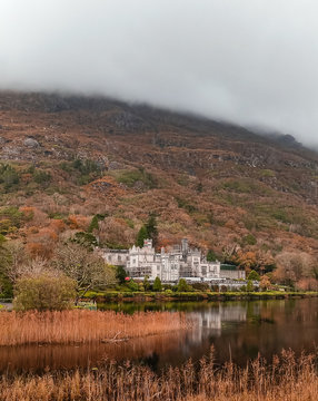 Kylemore Abbey in Connemara, Ireland. Autumn with Lough lake reflections at the bottom of Druchruach mountain. Benedictine monastery castle. 