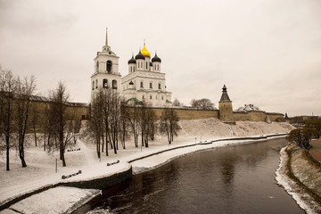 The old medieval fortress is covered with freshly fallen snow. Above the old walls rises the Cathedral and the bell tower. Pskov, Russia.