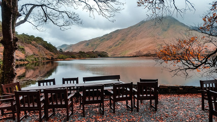 Kylemore Lough lake in Connemara, Ireland. Autumn view with outdoor seating for visitors at the...