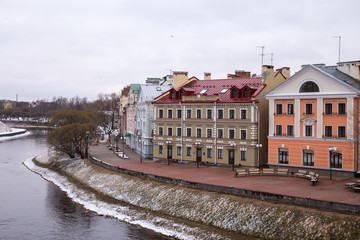 The embankment of the Pskov river is covered with fresh snow. Urban landscape with old houses. Pskov, Russia.