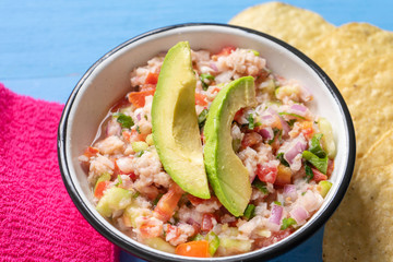 Mexican fish  ceviche with avocado on blue background