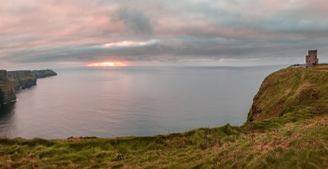 Cliffs of Moher, Ireland - panoramic view at sunset over sea cliffs next to O'Brien's Tower located at the southwest of the Burren region in County Clare.