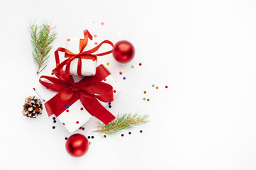 Christmas composition on a white background with white gift boxes, with a red ribbon with fir branches, toys, copy space for your congratulations