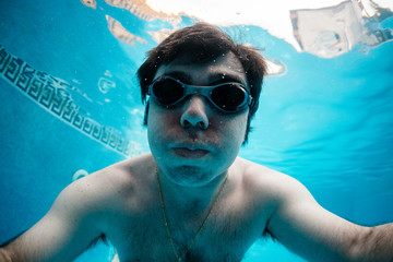 selfie de hombre joven en psicina haciendo apnea, buceando, nadando con gafas de natación
