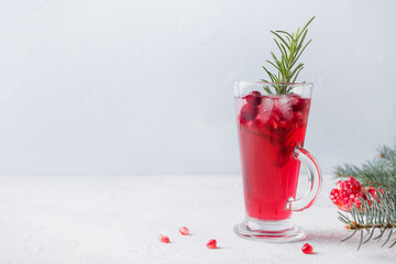 Pomegranate Christmas cocktail with rosemary, champagne, club soda on grey concrete table.
