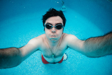 selfie de hombre joven en psicina haciendo apnea, buceando, nadando con gafas de natación