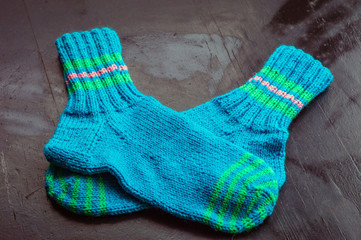 Warm multi-colored woolen knitted socks lie on the Black table.