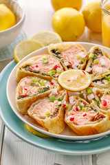 Puff pastry stuffed with salmon, spinach and dried tomatoes in portions drizzled with with lemon juice. Delicious appetizer, salmon roulade