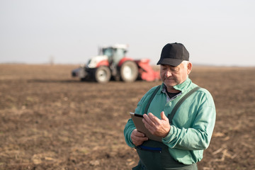 Modern senior farmer using tablet on the field
