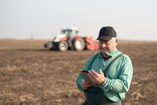 Modern senior farmer using tablet on the field - Powered by Adobe