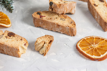 Traditional Italian biscotti or Cantuccini cookies with hazelnuts, almonds, walnuts on a gray background with slices of dried oranges and a Christmas tree. The concept of Christmas baking