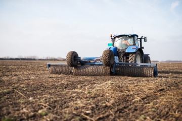 Obraz premium Tractor on the field cultivates the land.
