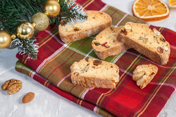 Traditional Italian Biscotti or Cantuccini cookies with hazelnuts, almonds, walnuts on a red-green napkin near the Christmas tree. Christmas and New Year baking.
