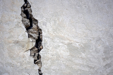 Big crack on the gray wall, abstract image of the vertical cleft. Close up.