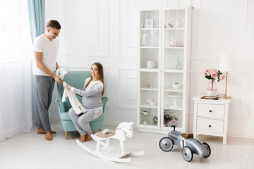 Young couple - man and woman expecting baby, looking at baby clothes. Awaiting the birth of a baby