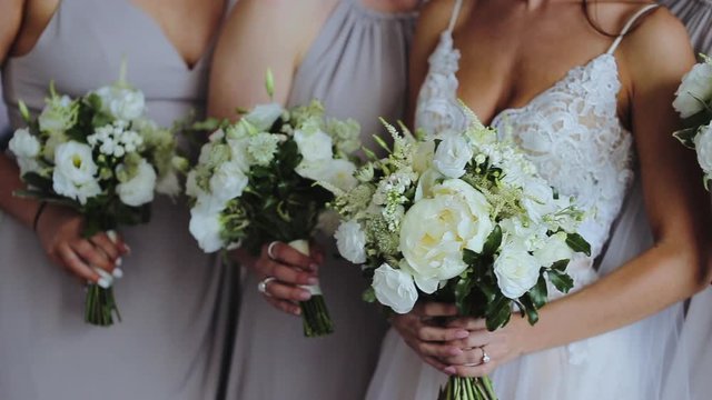 Close up side view of faceless bridesmaids holding wedding bouquet with white roses and eustoma (lisianthus)