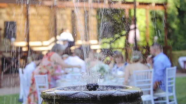 Fashionable wedding table decoration with white flower bouquets of roses and eustoma slow motion closeup, outdoor restaurant background