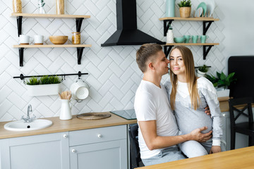 Young couple - man and woman expecting a baby, spend time in the kitchen. Awaiting the birth of a baby