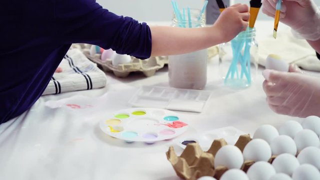 Time lapse. Little girl painting craft Easter eggs with acrylic paint.