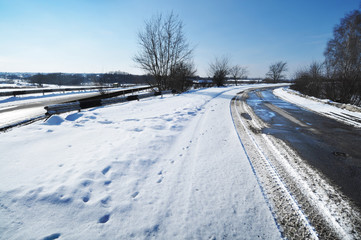 Fototapeta premium Winter countryside road with snow against blue sky