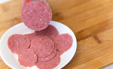 finely chopped salami in white plate on wood background