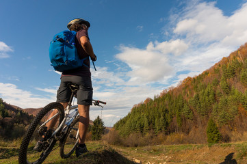 Mountain biker riding bike in the forest on dirt road. Mountain biker rides in autumn forest. Cycle trail in autumn forest. Mountain biking in autumn landscape forest