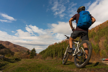 Mountain biker riding bike in the forest on dirt road. Mountain biker rides in autumn forest. Cycle trail in autumn forest. Mountain biking in autumn landscape forest