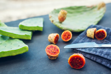 Prickly pear or cactus fruit cut with leaves. Exotic healthy food on grey background.