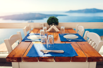 Romantic honeymoon dinner table served on Santorini island, Greece with seaside and mountains landscape, volcano view.
