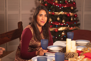 joven mexicana esperando cena enfrente de árbol de navidad