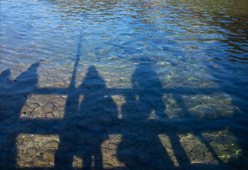 Shadows of the whole family, which are reflected in the Austrian lake, clear water, shimmering in the sun.