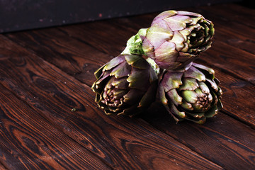 Obraz premium artichokes on rustic background. fresh raw organic artichoke flower.
