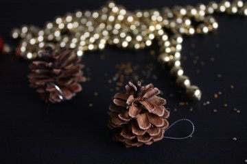 Christmas background. Christmas tree cones on a black background with sparkles.