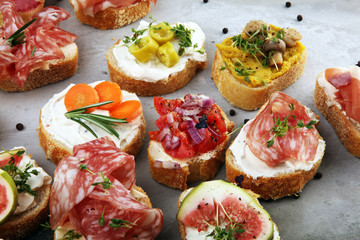 Fototapeta na wymiar Assorted bruschetta with various toppings. Appetizing bruschetta or brie crostini. Variety of small sandwiches. Mix bruschetta on table