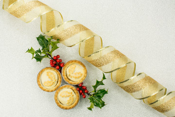 3  traditional British Christmas biscuit mince pie and Christmas tree branch with gold ribbon
