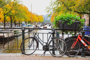 Fototapeta na wymiar Bicycles on a bridge over the canals of Amsterdam. Colorful houses and flowers. Autumn.