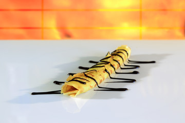 Naleśnik żółty z czekoladą na białym tle. © Stanisław Błachowicz