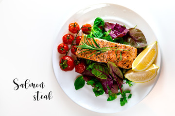 Salmon steak with lettuce, cherry tomatoes and lemon slices. Gala dinner. Food for lunch. Grilled red fish. Baked salmon in the oven