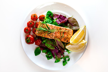 Salmon steak with lettuce, cherry tomatoes and lemon slices. Gala dinner. Food for lunch. Grilled red fish. Baked salmon in the oven