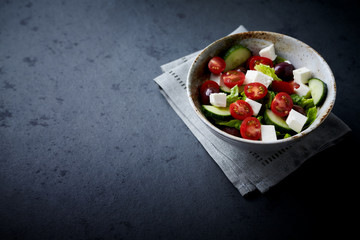 Salad with Kalamata Olives, Cucumber Cherry Tomatoes and Feta Cheese on black Stone Background. Healthy Snack Idea. Copy space. 