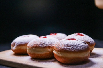 Hanukkah food doughnuts with jelly and sugar powder on black background. Jewish holiday Hanukkah concept and background. Copy space for text. Shallow DOF