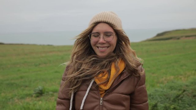 Close up portrait of Young Woman in hat smiling with hair blowing in wind in normand coast Slow Motion