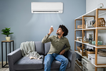 Man Adjusting The Temperature Of Air Conditioner