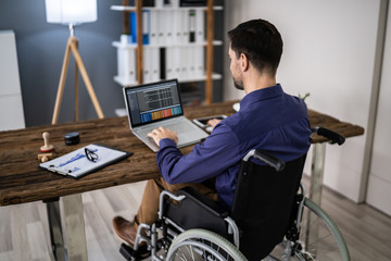 Businessman Sitting On Wheelchair And Using Computer