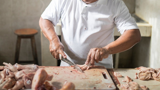 Man butchering chicken at a market in Cozumel, Mexico