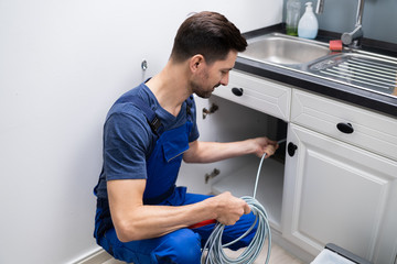 Plumber Cleaning Clogged Sink Pipe