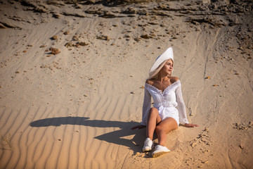 girl in white clothes sitting on the sand